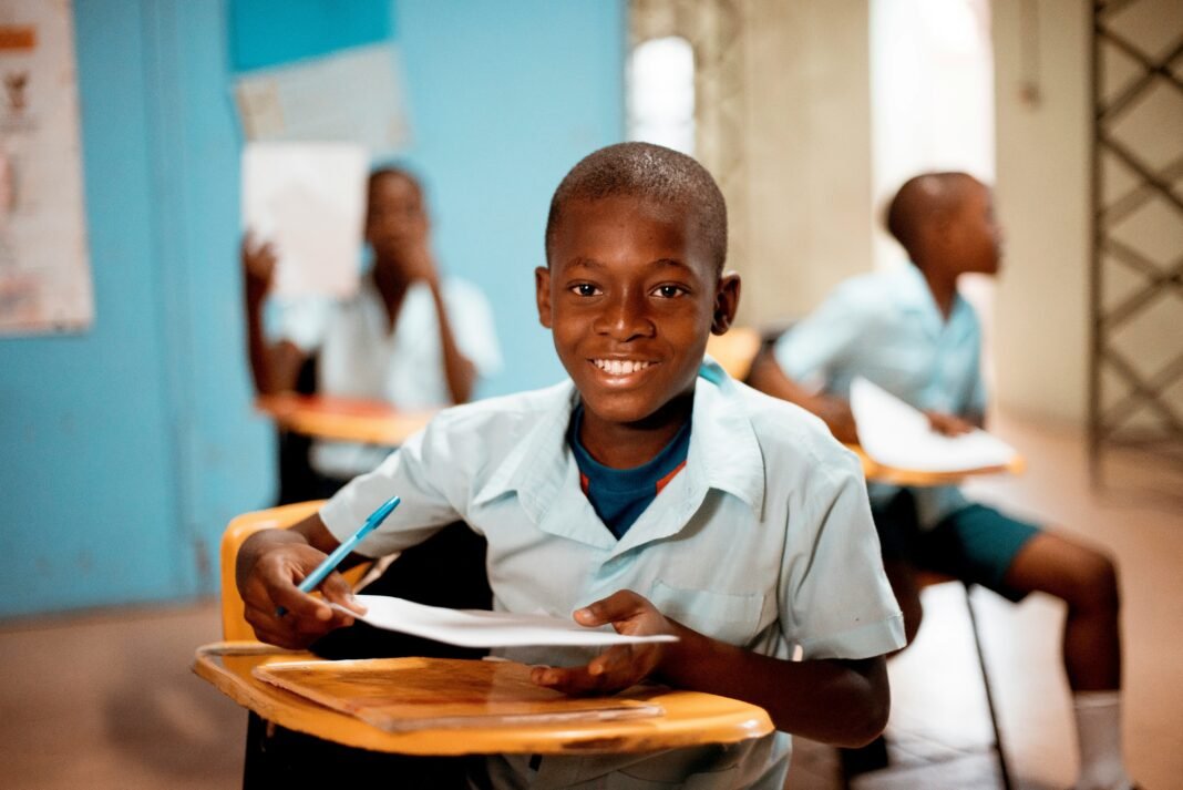African schoolboy smiling at his desk in a classroom