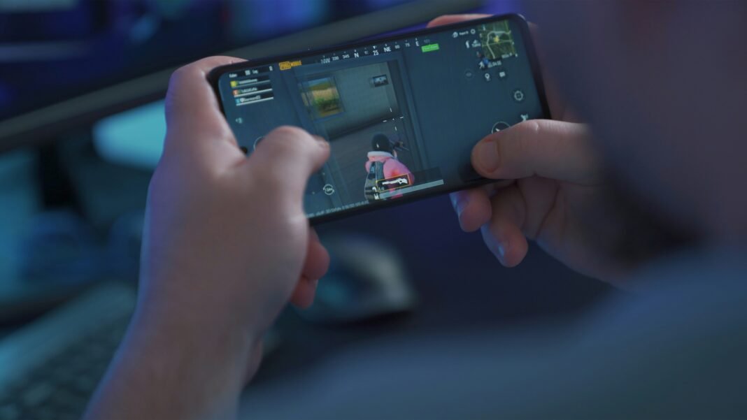 Close-up of hands holding a smartphone sideways while playing a game